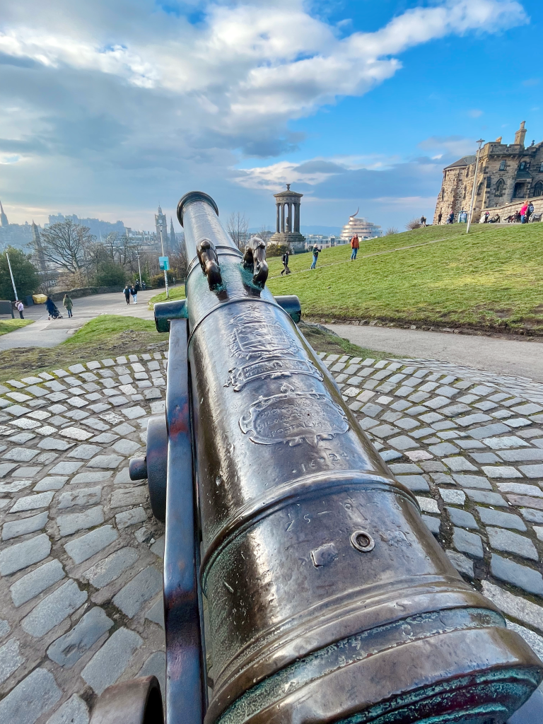 Portugese canon positioned on a stone platform, overlooking the cityscape in the background at Calton Hill.