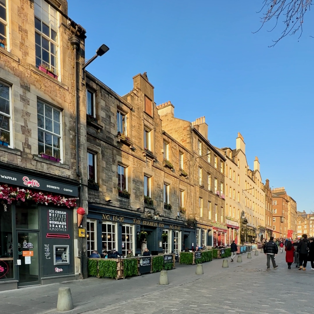 Colourful and Historic Grassmarket Street in Edinburgh, Scotland - Charming shops, restaurants, and pubs line the vibrant street surrounded by historic buildings, creating a lively atmosphere.