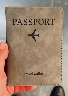 Light brown passport holder with “PASSPORT” and an airplane icon printed on the front. Sleek and functional travel stocking stuffer for keeping documents secure.