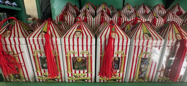 Close-up of several whimsical, red-and-white striped boxes of Bertie Bott’s Every Flavour Beans, each with a clear window showing the jelly beans inside and a red tassel on top.