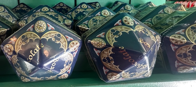 Stacks of hexagonal blue tins of Chocolate Frogs with ornate gold detailing and the words “Chocolate Frog” written across the top.