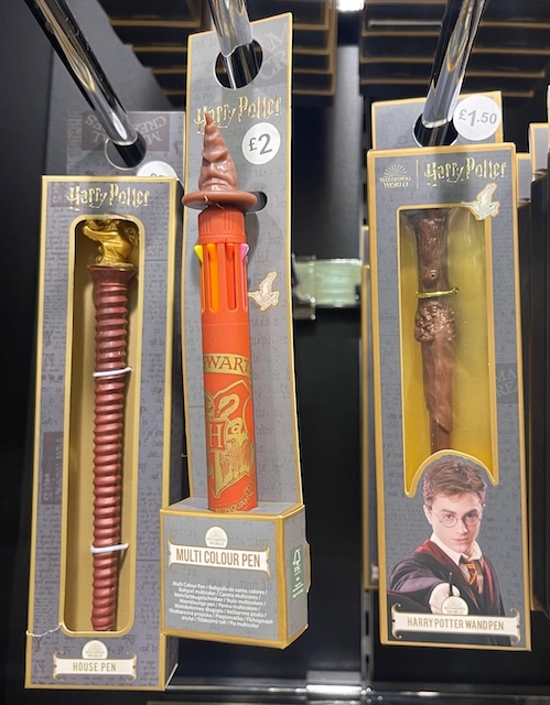 Three novelty pens styled as a Hogwarts house wand, the Sorting Hat, and Harry Potter’s wand, each boxed and hanging in a retail store
