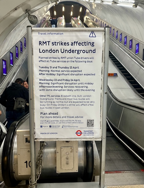 Travel information sign on a London Underground escalator warning that “RMT strikes affecting London Underground” will cause major Tube disruptions on listed dates.