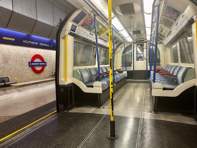 Nearly empty London Underground train stopped at Heathrow Terminal 4 station with platform signage visible through the open doors. The image shows one part of London's transport network that may be affected during a Tube strike.
