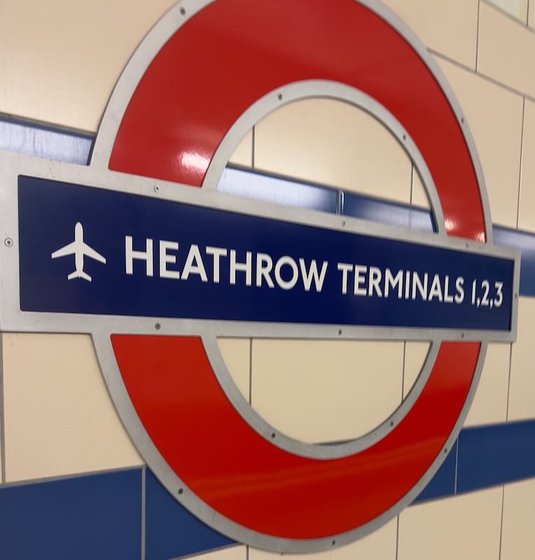 London Underground roundel sign at Heathrow Terminals 1, 2 and 3 station with the text "HEATHROW TERMINALS 1,2,3" and an airplane symbol. The station sign marks the starting point for travelers looking for how to get to Harry Potter Studios from Heathrow Airport.